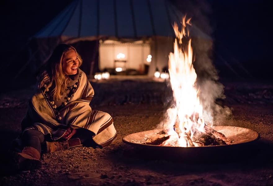 Traveller laughing beside a campfire at night